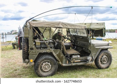 May 09 2014 Brisbane Australia  Living History Reenactment - WW2 Jeep With Antennas Tied Down And Shovel Secured To Side - Man In Army Uniform With Painted Face Gives Thumbs-up - Tents & River Behind 