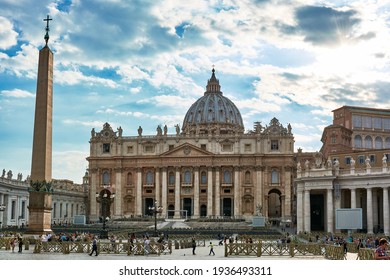 MAY 17, 2017 - ROME, ITALY: View of Saint Peter's Basilica exterior facade with sculptures, obelisk and dome. People walking at St. Peter's square under blue cloudy sky on a spring day.