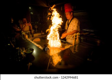 May, 2018 - Ari Atoll, Maldives: Happy Teppanyaki Chef Cooking Vegetables At Teppan In A Japanese Steakhouse On Mishi Sushi. Gourmet Food In Luxury Restaurant. Kitchen Cooking Show, Professional Chef