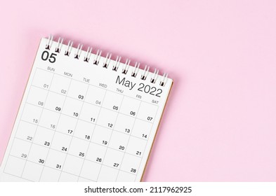 May 2022 desk calendar on pink background with empty space.