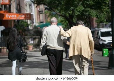 May 27, 2017.  New York City, New York.   Two Elderly Men Help Each Other Walk Down A Manhattan City Street. 