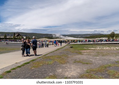 May 27 2018 - Yellowstone National Park, WY: Crowds Of Tourists And Visitors Wait For Old Faithful Geyser To Erupt. Family Taking Selfie With A Smart Phone In The Foreground