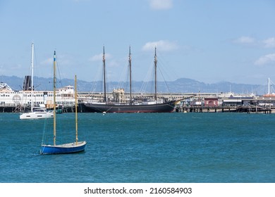 May 8, 2022 San Francisco, California. Dramatic image of old historical boats and ships on the bay docked on a pier, with bay in foreground and pier 39 in background.