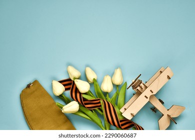 May 9. St.George ribbon, wooden plane,military cap, white tulips on a blue background. The traditional symbol of Victory Day 1945. Victory Day holiday. Banner. Postcard. Flat lay, copy space  - Shutterstock ID 2290060687
