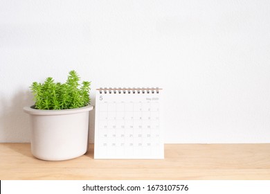 May calendar 2020with green plant in pot on wooden table - Shutterstock ID 1673107576