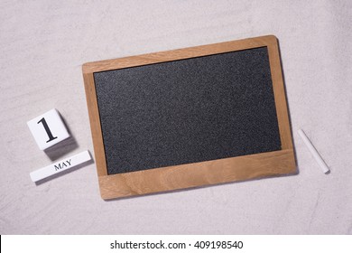 May Day, May 1. May 1st. White Wooden Blocks With Black Chalkboard Over Sandy Background. Labor Day Or Holiday Concept