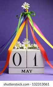 May Day, May 1, White Block Calendar With Maypole And Rainbow Color Ribbons And Flowers Against A Purple Background.