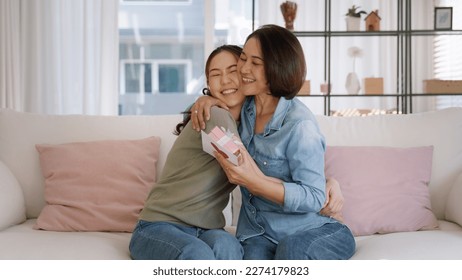 May Mother's day young adult grown up child cuddle hug give flower gift box red heart card to mature middle aged mum. Love kiss care mom asia people sitting at home sofa happy smile enjoy family time. - Shutterstock ID 2274179823