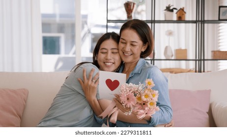 May Mother's day young adult grown up child cuddle hug give flower gift box red heart card to mature middle aged mum. Love kiss care mom asia people sitting at home sofa happy smile enjoy family time. - Powered by Shutterstock