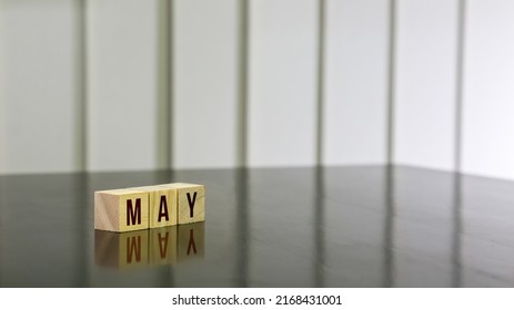 MAY Word On Wooden Cube On Black Gloss Wooden Table. Selected Focus