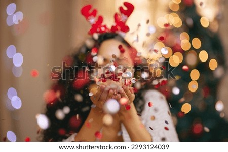May you jingle ALL the way. a young woman blowing confetti during Christmas at home.
