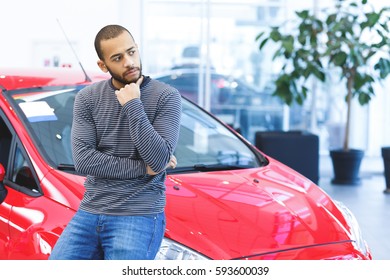 Maybe This One? Thoughtful Handsome Young African Man Rubbing His Chin Choosing A Car To Buy At The Dealership Copyspace Buyer Shopping Shopper Consumer Consumerism Lifestyle Travel People Concept