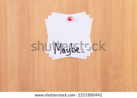 MAYBE.. - White Sticky Notes with Written Word MAYBE, Pinned to the Wooden Message Board. To Do List Reminder in the Office. Memo Note at Work