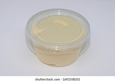 Mayonnaise in plastic cup on white background.