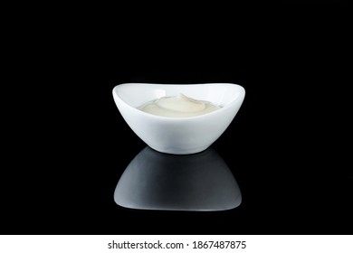 mayonnaise in a white bowl on a black background.