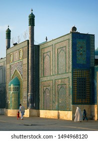 Mazar-i-Sharif, Balkh Province In Afghanistan: An Afghan Family Walks Past The Blue Mosque In Mazar I Sharif In The Sunshine. Colorful Mosaics And Tiles Adorn The Mosque Walls. Northern Afghanistan.