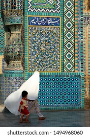 Mazar-i-Sharif, Balkh Province / Afghanistan - Aug 31 2005: A Woman In A White Burqa (burka) With A Child Walks Past The Blue Mosque In Mazar I Sharif. Mosaics Adorn The Walls. Northern Afghanistan.