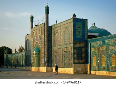 Mazar-i-Sharif, Balkh Province In Afghanistan. A Man Walks Past The Blue Mosque In Mazar I Sharif In The Sunshine. Colorful Mosaics And Tiles Adorn The Mosque Walls. Northern Afghanistan.