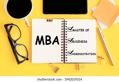 MBA - Master Of Business Administration, Text On Notepad And Office Accessories On Yellow Desk.