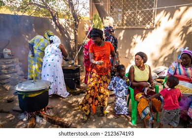 MBOUR, SENEGAL - Circa DECEMBER 2021. Unidentified women dressed with colorful traditional clothes cooking in outdoor kitchen with rudimentary utensil but great food. Poverty in Africa