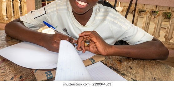 MBOUR, SENEGAL - DECEMBER Circa, 2021. Unidentified Young Child Writing Letter To Godfather Or Godmother Because European NGO Help Him To Pay School And Food For Family. Close-up On Hands