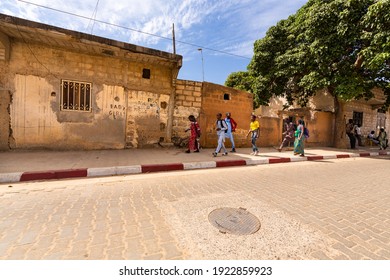 MBOUR, SENEGAL - JANUARY Circa, 2021. Unidentified School Aged Girls And Boys With Backpack Walking In The Poor Village After School In Sunny Spring Day. No Face Mask During Covid 19 Pandemy.