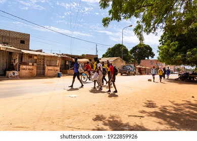 MBOUR, SENEGAL - JANUARY Circa, 2021. Unidentified School Aged Girls And Boys Students With Backpack Walking In The Poor Village After School In Sunny Spring Day. No Face Mask During Covid 19 Pandemy.