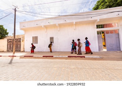 MBOUR, SENEGAL - JANUARY Circa, 2021. Unidentified School Aged Girls With Backpack Walking In The Poor Village After School In Sunny Spring Day. No Face Mask During Covid 19 Pandemy.