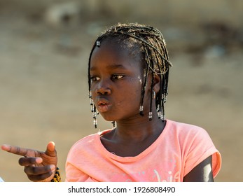 MBOUR, SENEGAL - JANUARY Circa, 2021. Portrait Of Unidentified Young Senegalese Children, Not Looking At Camera. Beautiful Skin, Hairs, Light. Outdoors