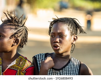 MBOUR, SENEGAL - JANUARY Circa, 2021. Portrait Of Unidentified Young Senegalese Children, Not Looking At Camera. Beautiful Skin, Hairs, Light. Outdoors