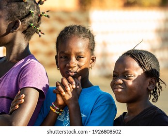 MBOUR, SENEGAL - JANUARY Circa, 2021. Portrait Of Unidentified Young Senegalese Children, Not Looking At Camera. Beautiful Skin, Hairs, Light. Outdoors