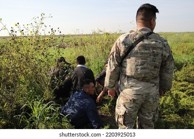 McAllen, TX, USA - Sept. 9, 2022: A Member Of The Texas National Guard Guards Five Mexican Men Who Were Apprehended After Crossing The Rio Grande River Illegally.