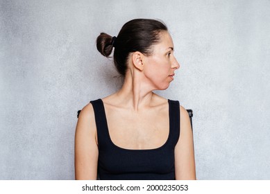 McKenzie Method Exercise To Relieve Neck Pain, A Woman Gently Rotates Her Head While Doing Neck Pain Relief Exercises