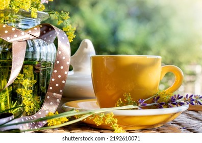 Meadow Flowers In A Glass Vase, A Yellow Cup Of Coffee On A Garden Table In The Rays Of The Setting Sun. Rest, Relaxation In Summer Concept. A Natural Romantic Scene