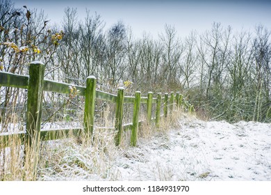 Meadow With Green Wooden Fence On British Countryside Covered With Snow On Beautiful Winter Day.Bare Trees In Background.Winter Wonderland Scenery.Idyllic Landscape Of Rural Staffordshire,Uk.