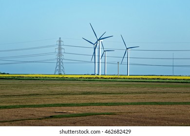 Meadow With Wind Mill Turbines Generating Electricity And Electric Power Lines, In England, The UK