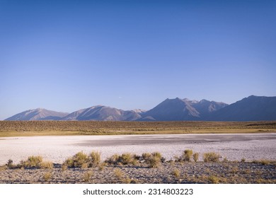 Meadows and empty fields surrounded by mountains and covered with salt residue close to Mammoth Lakes in Eastern Sierra, California