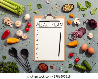 Meal plan concept. Food ingredients, salad serving utensils and clipboard with letters MEAL PLAN and seven numbers. Gray background. Diet menu concept. Top view, flat lay