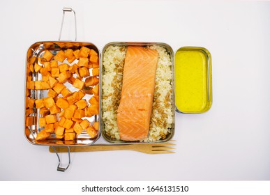 Meal Of Sweet Potatoes, Cauliflower Rice, Pine Nuts, Salmon, And Mustard Color Sauce In Metal Bento Box