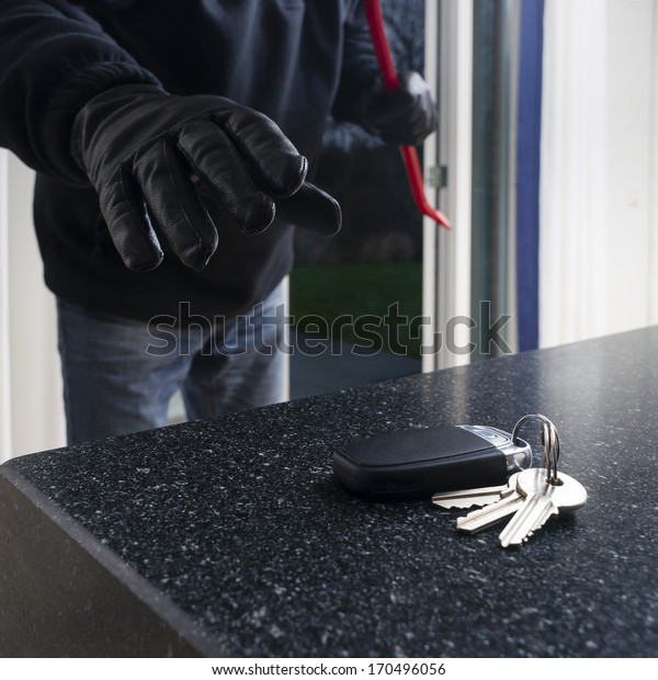 Mean looking burglar enters a kitchen to\
grab the car key from the kitchen\
counter