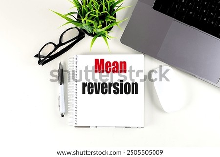 MEAN REVERSION text on a notebook with laptop, mouse and pen . 