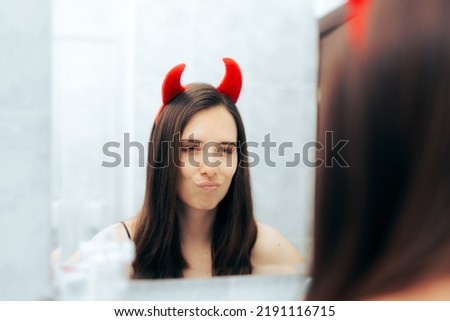 
Mean Woman with Devil Horns Looking in the Mirror. Evil narcissistic person checking herself with infatuation and arrogance
