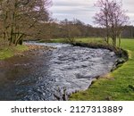 A meander in the River Dunsop near Dunsop Bridge in Lancashire, UK. On the left rock debris on the slip-off slope is visible while on the right, lateral erosion has formed a small river cliff.
