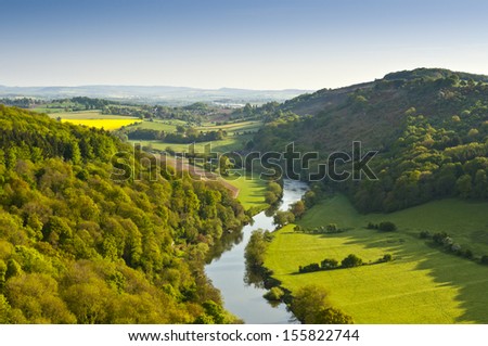 Meandering River Wye making its way through lush green rural farmland in the warm early sunlight.