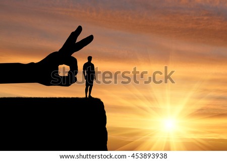 Meanness and treachery concept. Silhouette hand wants to push a man off a cliff