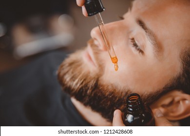 Means For Caring Beard Oil, Barber Puts On Face Of Man.