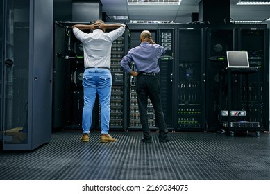 Meanwhile in the server room.... Rearview shot of two IT technicians having difficulty repairing a computer in a data center. - Powered by Shutterstock