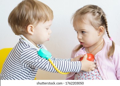 measure the temperature. high temperature, Covid - 19.Two kids play doctor in the nursery.Brother treats his sister, playing dentist, ENT, ophthalmologist Role-playing games check of heartbeat, breath