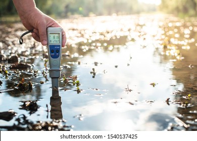 Measure water content with digital device. Sunrise over the water. PH meter. - Powered by Shutterstock