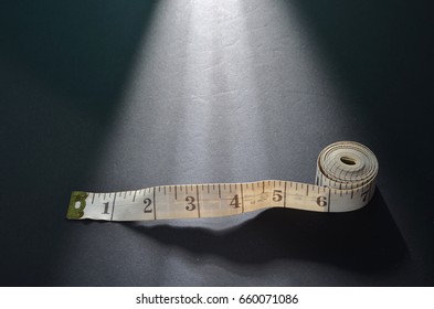 Measurement Tape On Top Of Black Back Ground. Studio Shoot With Creative Lighting